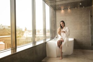woman in white bathrobe sitting on white bathtub