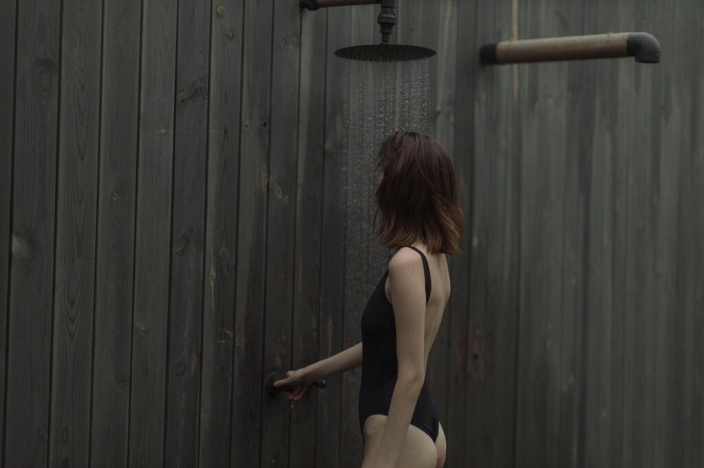 woman in black one piece swimsuit taking a shower