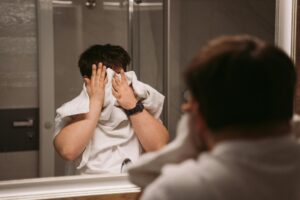 man in white shirt using towel to wipe the face